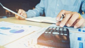 funcionário a organizar finanças da empresa com papéis e uma calculadora.