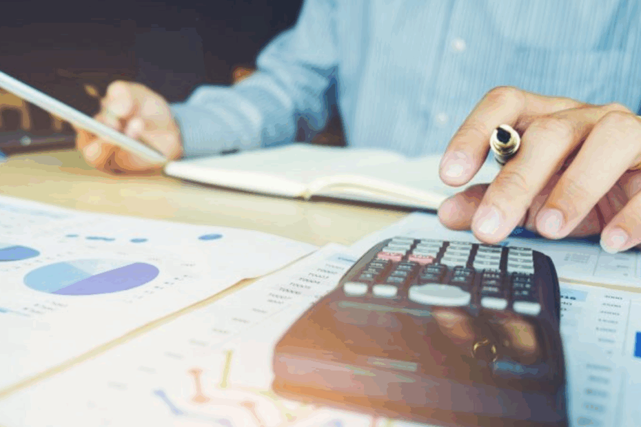 funcionário a organizar finanças da empresa com papéis e uma calculadora.
